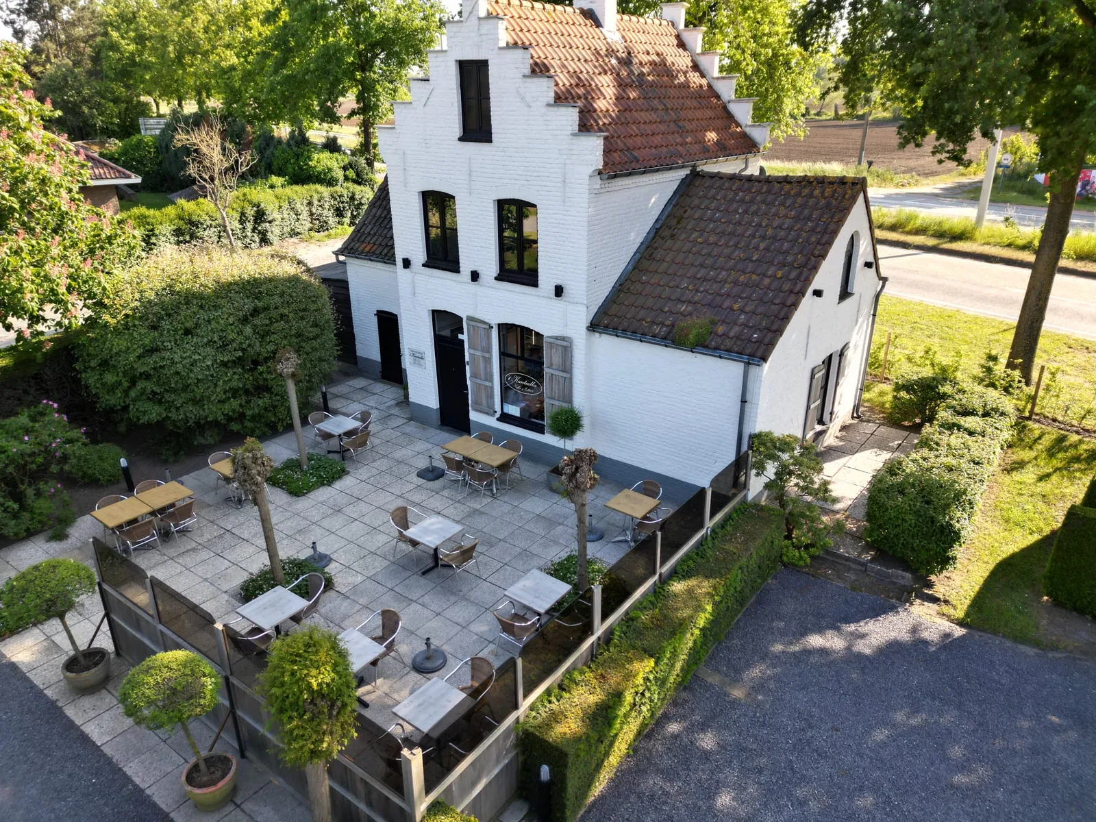 ’t Kanteelke: het witte gebouw met trapgevels en het groene terras met tafels en stoelen